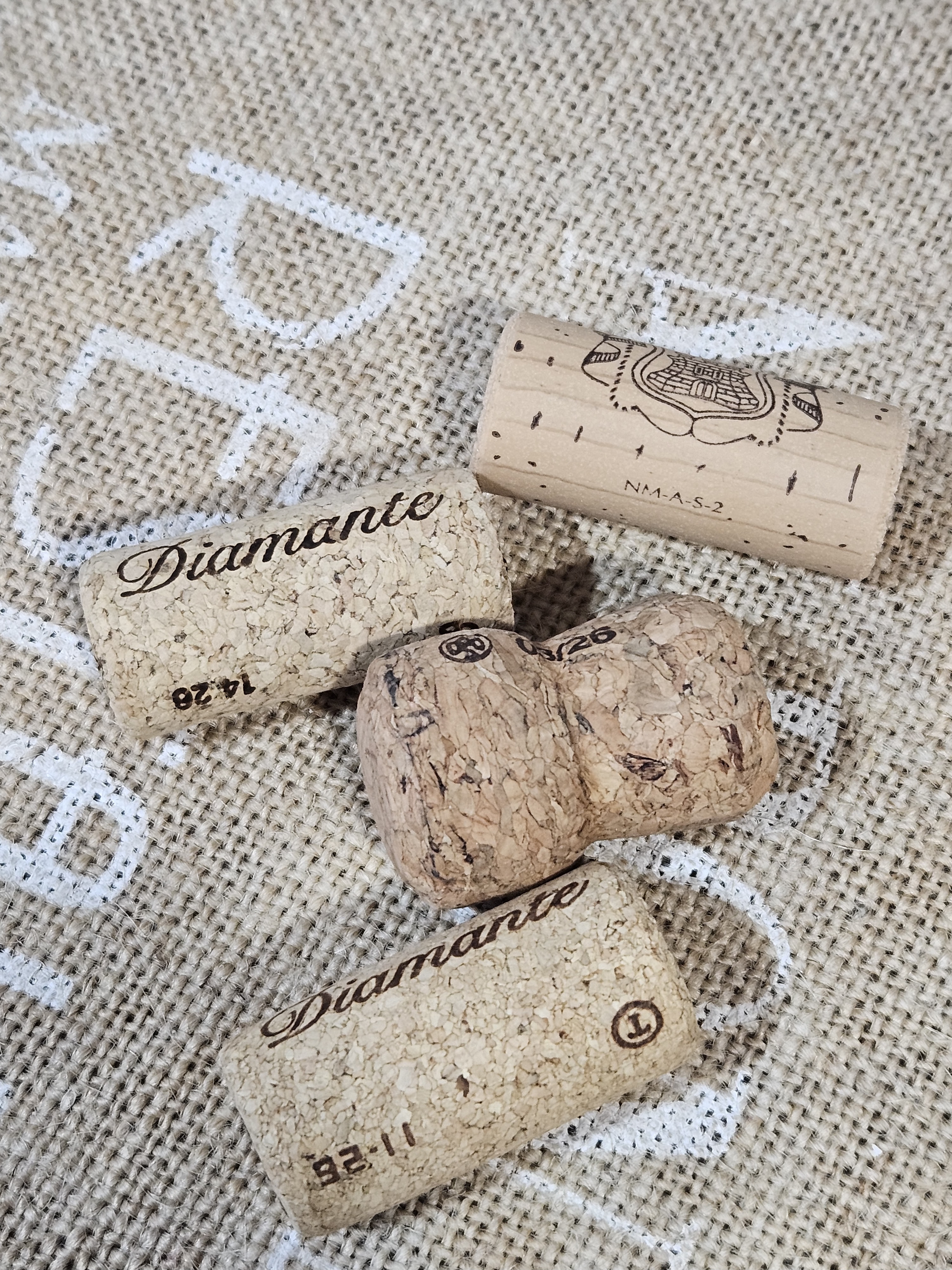 Three wine corks on a textured fabric surface with the word Diamante printed on two of them